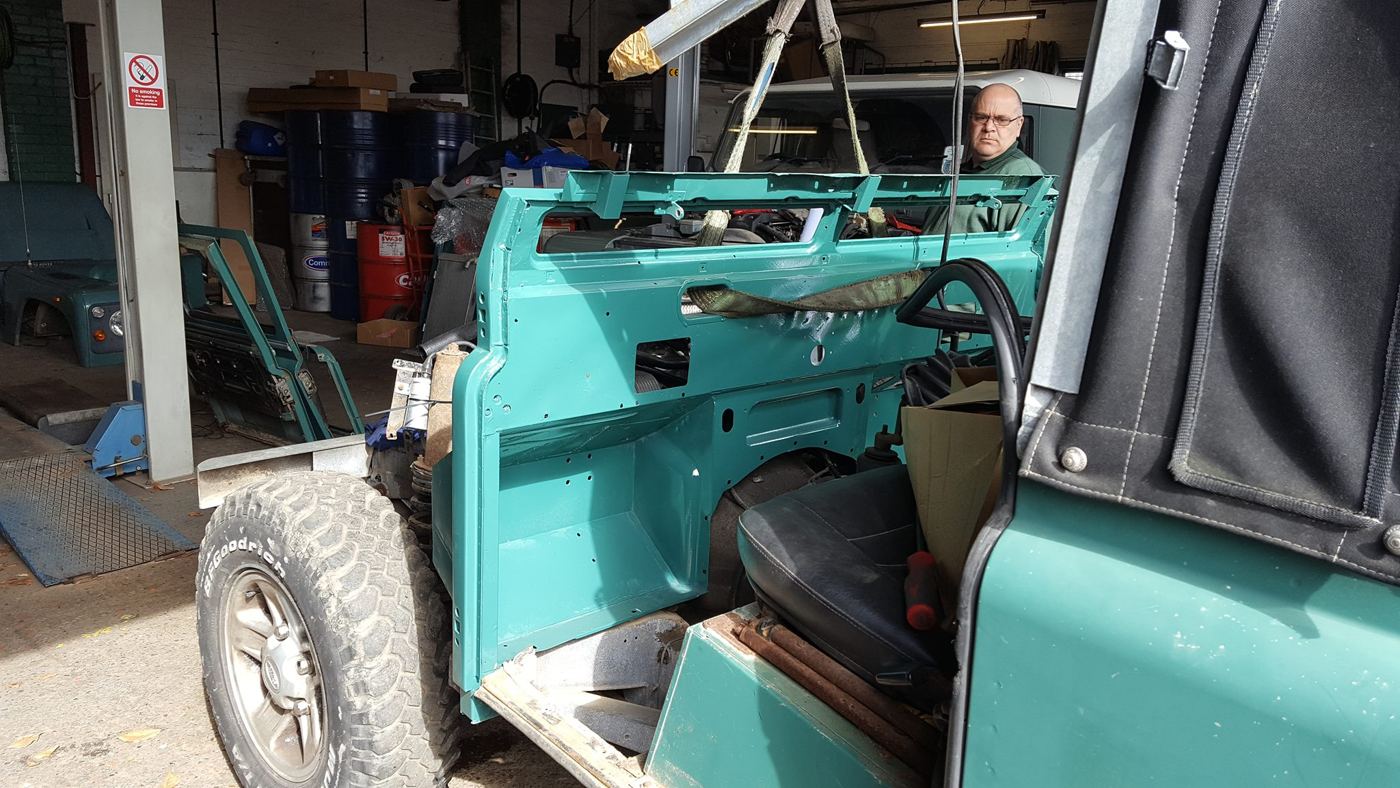 Freshly painted bulkhead being fitted to a Land Rover in the workshop